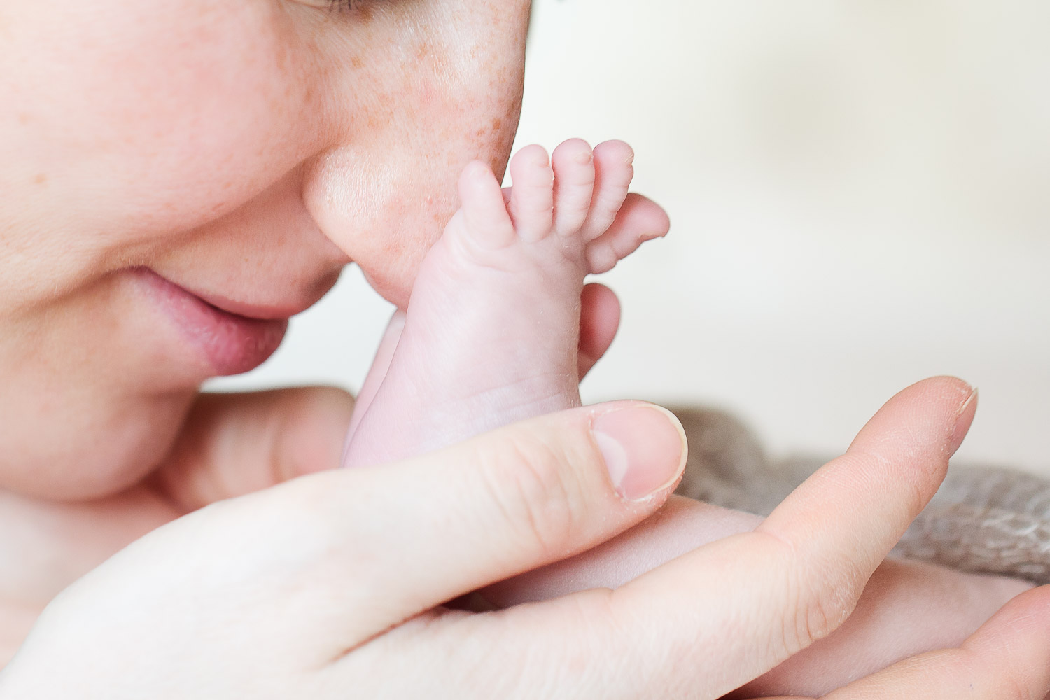 Closeup of newborns foot and mothers face