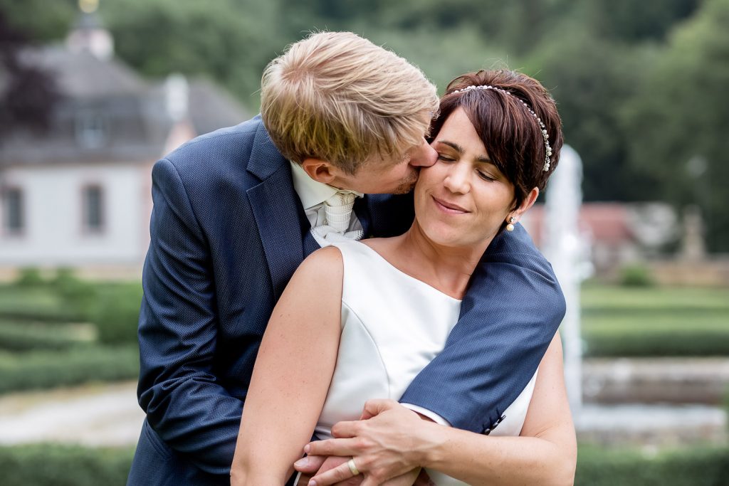 Groom kisses the bride in the garden of Schloss Weilerbach, Hochzeit, wedding, Andrea Schenke Photography